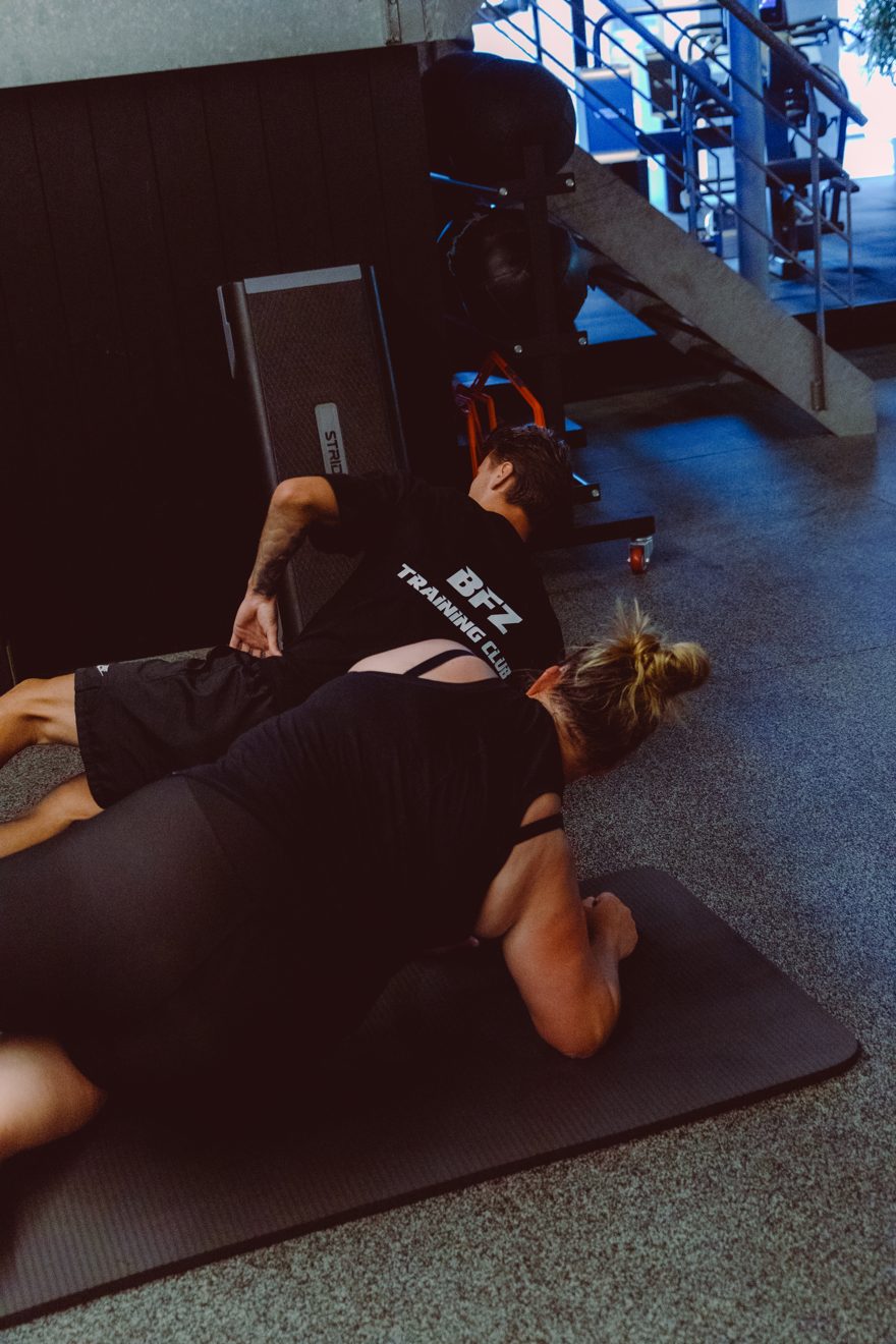 Coach Jarno guides a member through floor work, hands-on